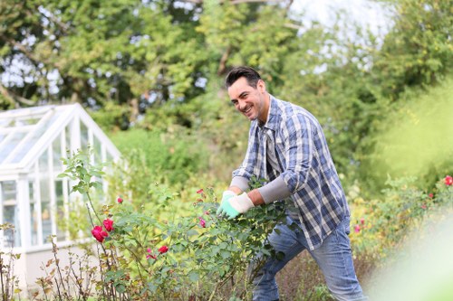 Worker using powered hedge trimmer with protective gear